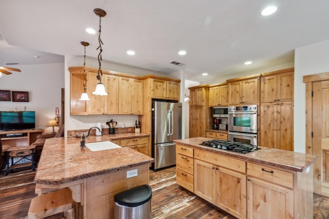 kitchen with sink, hanging light fixtures, stainless steel appliances, kitchen peninsula, and a kitchen bar