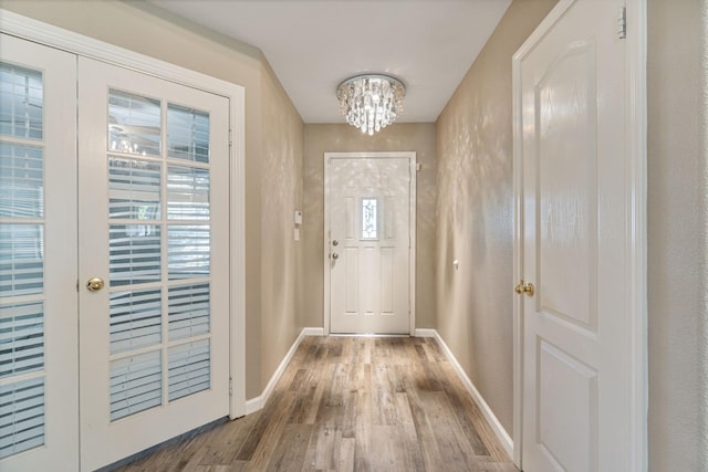 doorway to outside with a chandelier, french doors, wood finished floors, and baseboards