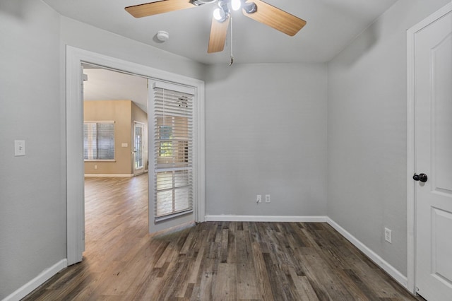 spare room with dark wood-type flooring, ceiling fan, and baseboards