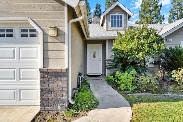 view of exterior entry featuring a garage and a shingled roof