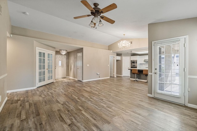 unfurnished living room with lofted ceiling, baseboards, and wood finished floors