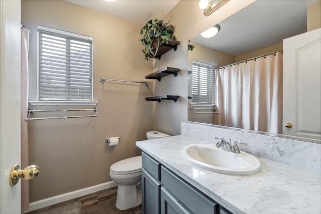 bathroom with toilet, vanity, wood finished floors, a shower with curtain, and baseboards