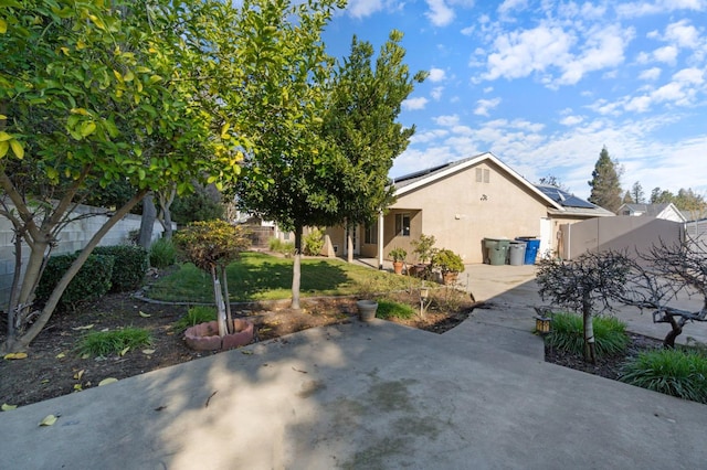 exterior space featuring roof mounted solar panels, fence, a lawn, and stucco siding