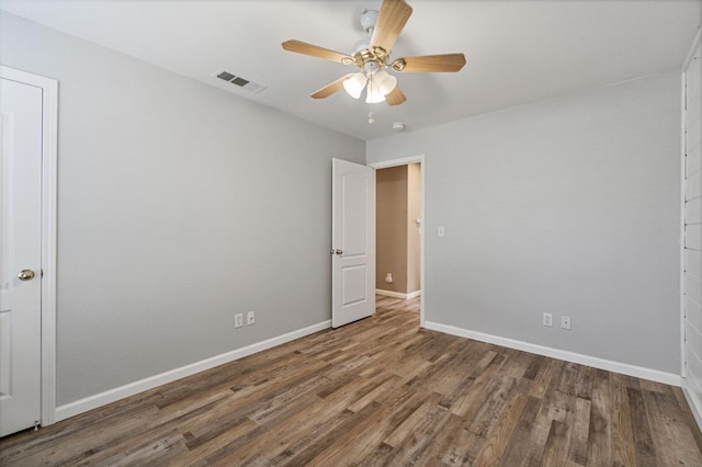 spare room with a ceiling fan, wood finished floors, visible vents, and baseboards