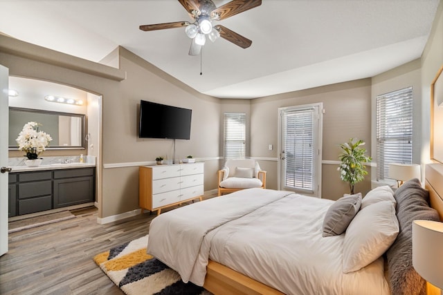 bedroom with multiple windows, vaulted ceiling, ensuite bath, and light wood finished floors