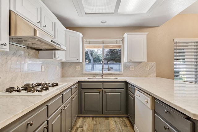 kitchen featuring white appliances, a sink, under cabinet range hood, and gray cabinetry