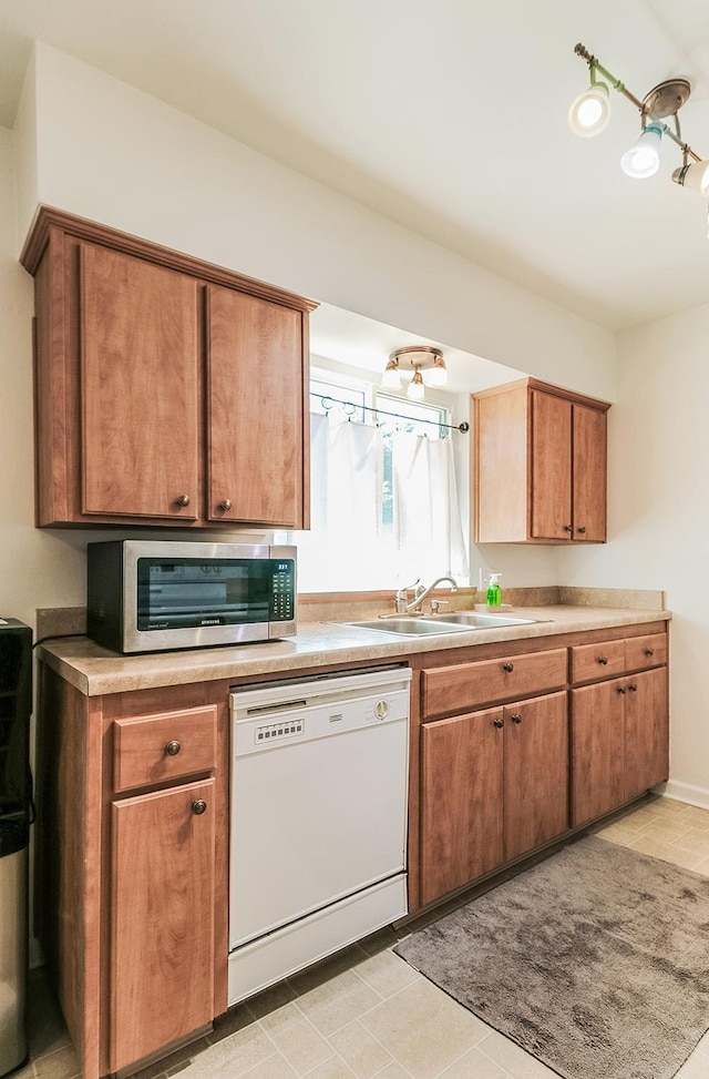 kitchen featuring sink, white dishwasher, and light tile patterned flooring