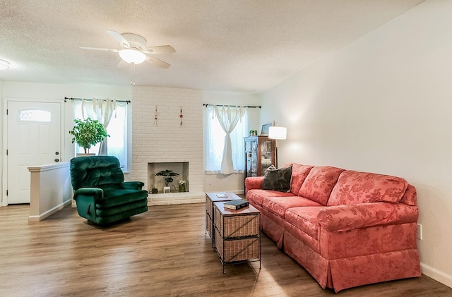 living room featuring ceiling fan, plenty of natural light, dark wood-type flooring, and a textured ceiling