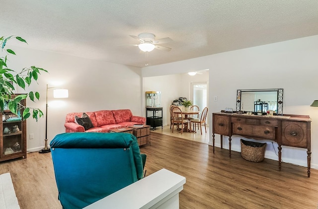 living room featuring ceiling fan, wood-type flooring, and a textured ceiling