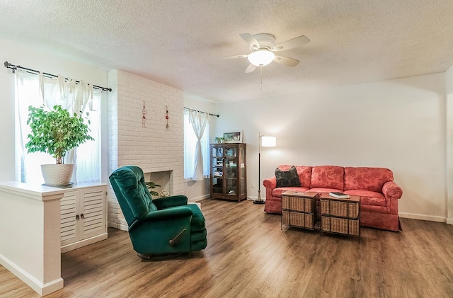 living room featuring hardwood / wood-style flooring, ceiling fan, a fireplace, and a textured ceiling