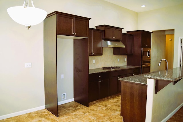 kitchen with stainless steel appliances, ventilation hood, dark stone countertops, decorative light fixtures, and a center island with sink