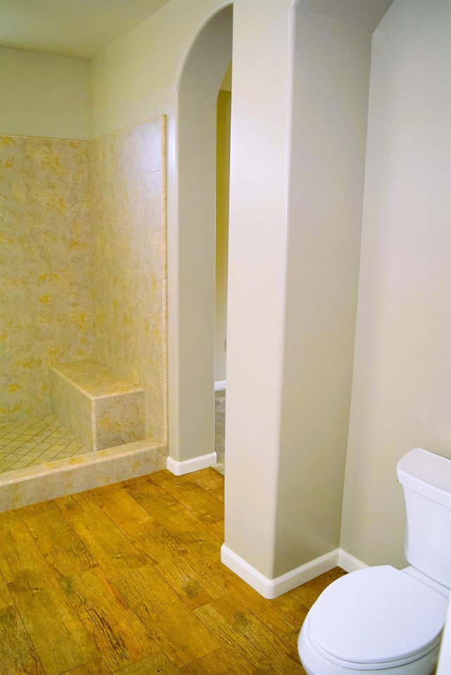 bathroom featuring tiled shower, wood-type flooring, and toilet