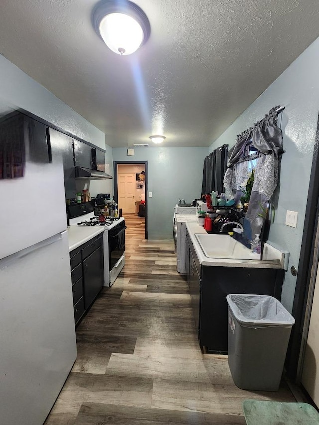 kitchen with sink, gas range, a center island, white refrigerator, and dark hardwood / wood-style flooring