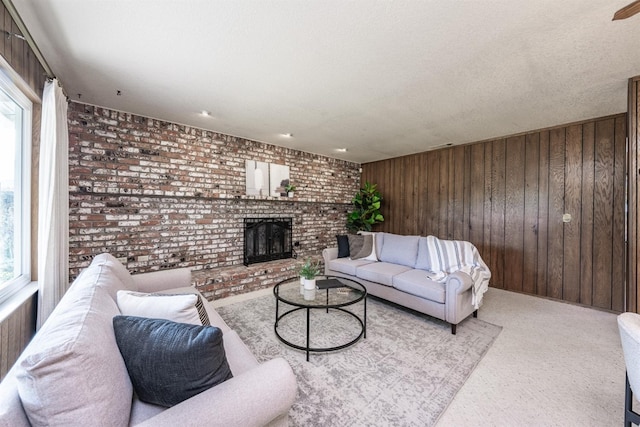 carpeted living room featuring plenty of natural light, wood walls, a fireplace, and brick wall