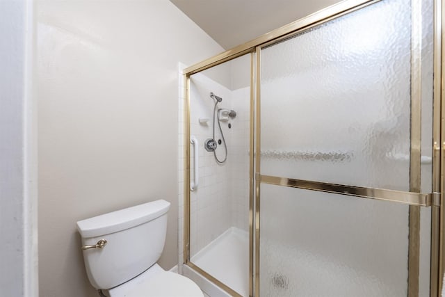 bathroom featuring a shower with door and toilet