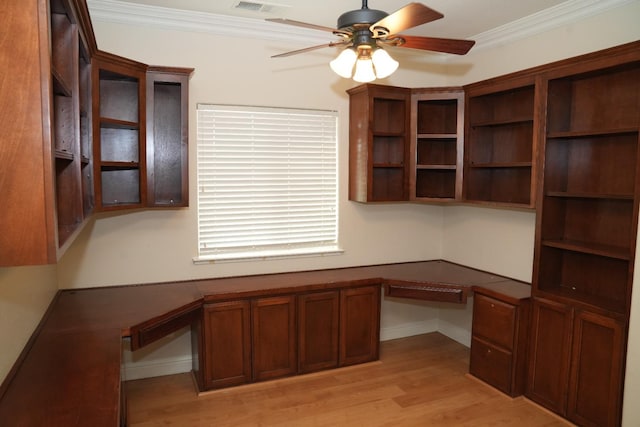 unfurnished office featuring ceiling fan, light hardwood / wood-style floors, built in desk, and ornamental molding