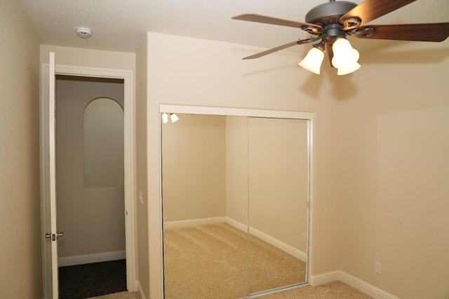 unfurnished bedroom with ceiling fan, light colored carpet, and a closet