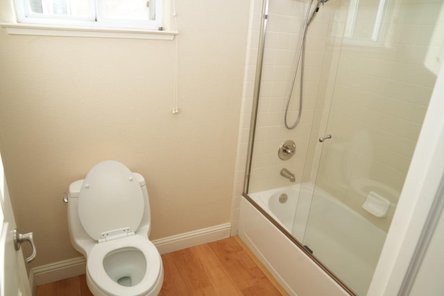 bathroom with shower / bath combination with glass door, hardwood / wood-style floors, and toilet