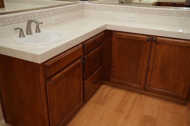 bathroom with decorative backsplash, wood-type flooring, and vanity