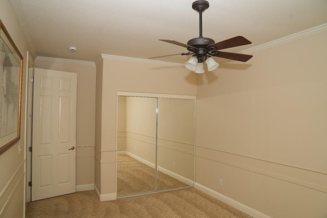 unfurnished bedroom with ceiling fan, light colored carpet, crown molding, and a closet