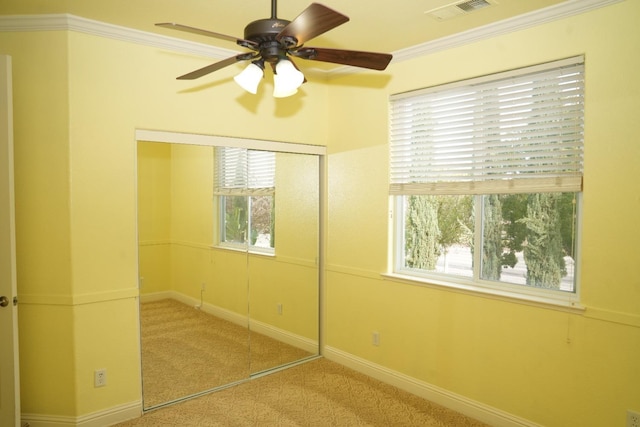 unfurnished bedroom with ceiling fan, ornamental molding, light carpet, and a closet