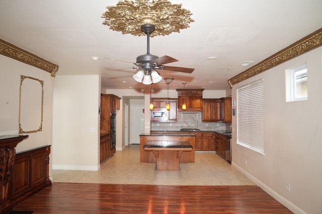 kitchen featuring a kitchen breakfast bar, tasteful backsplash, ceiling fan with notable chandelier, stainless steel appliances, and light tile patterned flooring