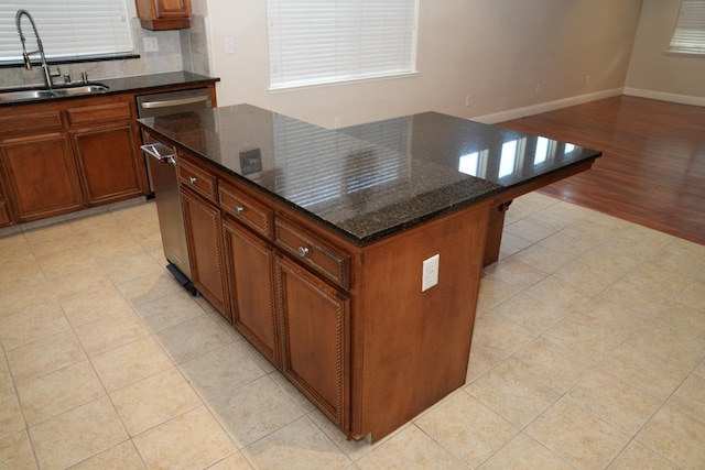 kitchen with light tile patterned flooring, sink, a kitchen island, and dark stone counters