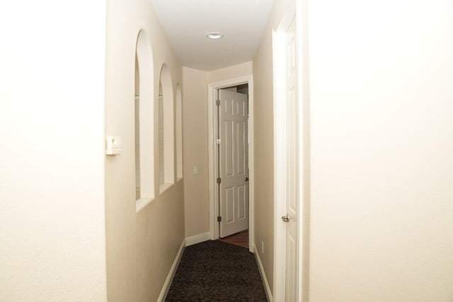 corridor featuring dark colored carpet