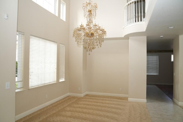 empty room featuring light colored carpet, a wealth of natural light, and a chandelier