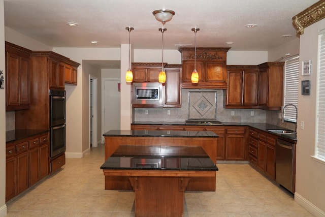 kitchen with a kitchen breakfast bar, stainless steel appliances, sink, a kitchen island, and hanging light fixtures