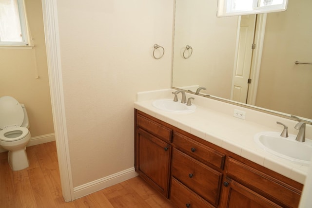 bathroom featuring plenty of natural light, vanity, wood-type flooring, and toilet