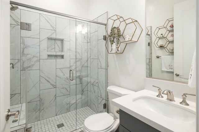 bathroom featuring vanity, toilet, and a shower with door