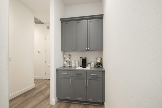 bar with gray cabinetry and hardwood / wood-style flooring