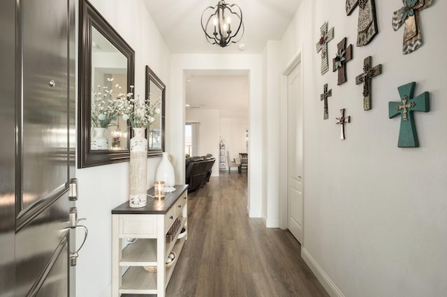 hallway with dark hardwood / wood-style flooring and an inviting chandelier