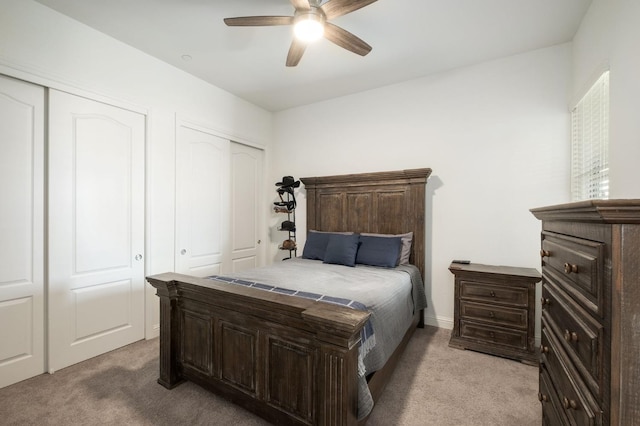 carpeted bedroom featuring ceiling fan and multiple closets