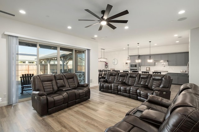 living room featuring a wealth of natural light, light wood-type flooring, and ceiling fan