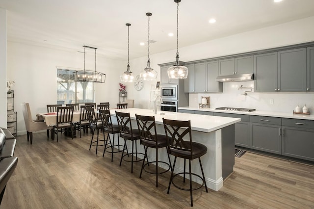 kitchen featuring pendant lighting, stainless steel appliances, and an island with sink