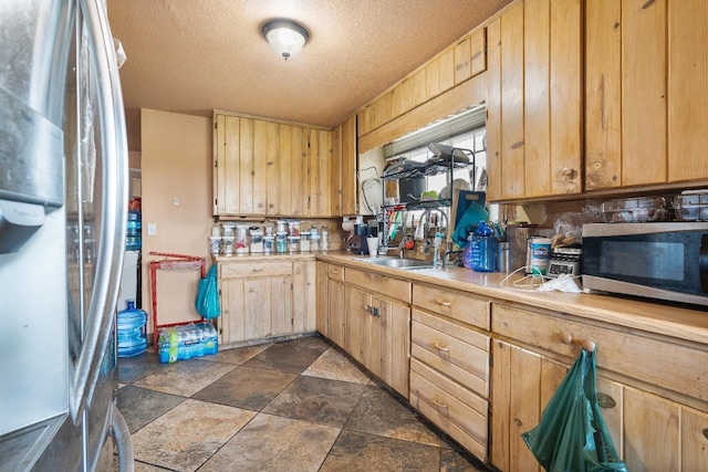 kitchen featuring light brown cabinetry, stainless steel appliances, and a textured ceiling