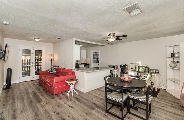 dining space featuring ceiling fan, french doors, a textured ceiling, and hardwood / wood-style flooring