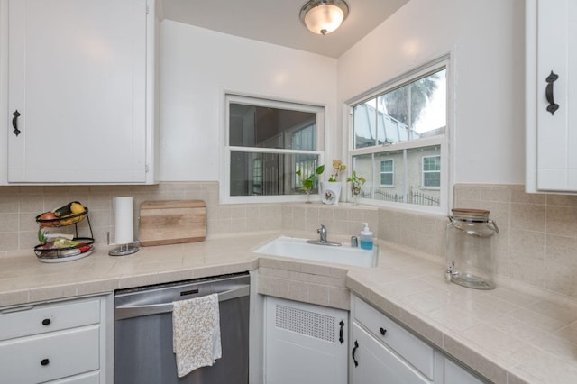 kitchen featuring sink, white cabinetry, stainless steel dishwasher, and tile countertops