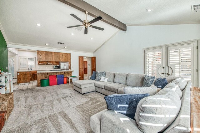 living room with ceiling fan, lofted ceiling with beams, a textured ceiling, ornamental molding, and light carpet