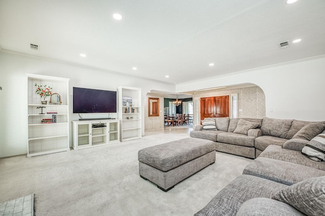 carpeted living room featuring ornamental molding and a chandelier