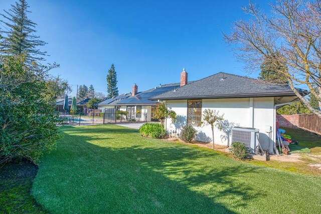 back of house with central air condition unit and a lawn