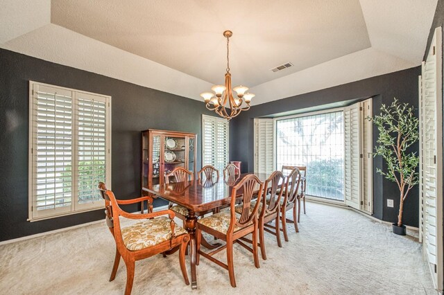 carpeted dining room with vaulted ceiling, a raised ceiling, and an inviting chandelier