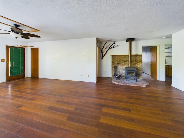 unfurnished living room with ceiling fan, a textured ceiling, dark hardwood / wood-style floors, and a wood stove