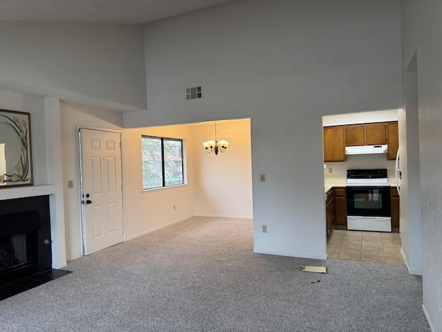 unfurnished living room featuring light colored carpet, an inviting chandelier, and a towering ceiling