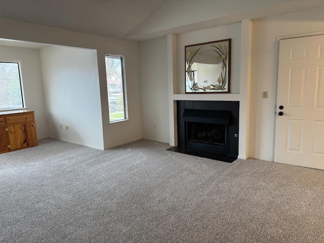 unfurnished living room featuring lofted ceiling, a tile fireplace, a textured ceiling, and carpet