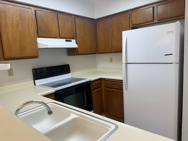 kitchen with electric range, white refrigerator, and sink