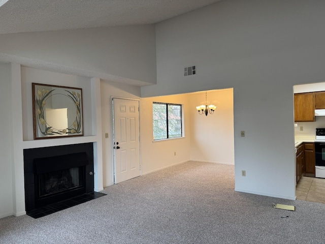 unfurnished living room featuring a textured ceiling, high vaulted ceiling, an inviting chandelier, and light carpet