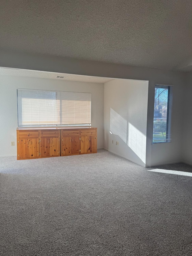 carpeted empty room with a textured ceiling